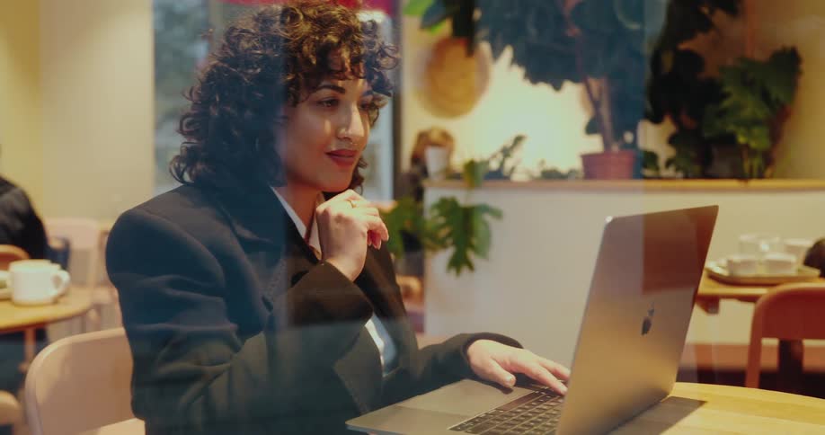 A woman is sitting in a restaurant typing on her laptop