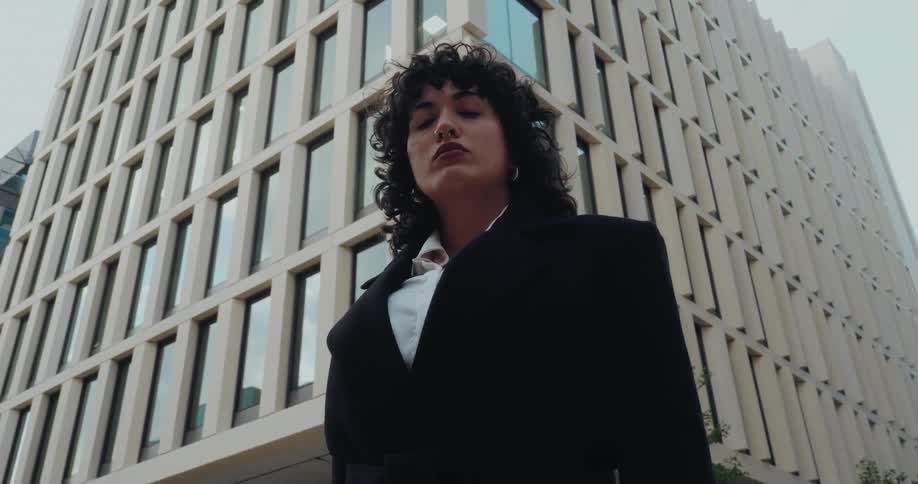 Woman in a confident stance poses in front of a corporate building