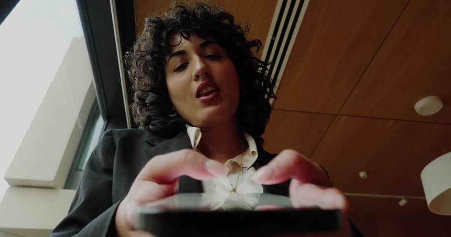 Woman types on her phone seen from below in a corporate setting