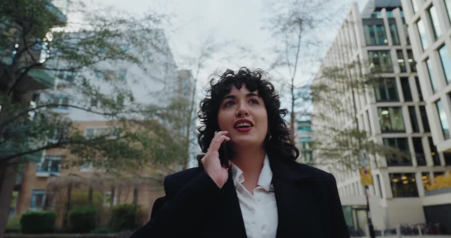 A woman is walking down a city street as she talks on her phone