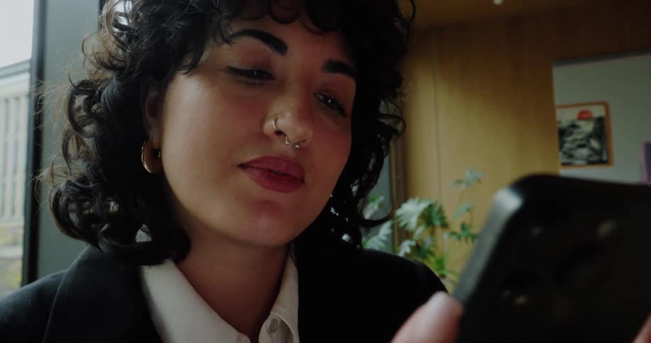 Woman looks closely at her phone inside the office