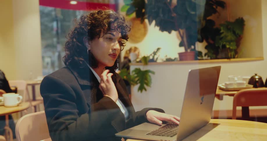 Woman works on her laptop while seated in a caf as seen through the window
