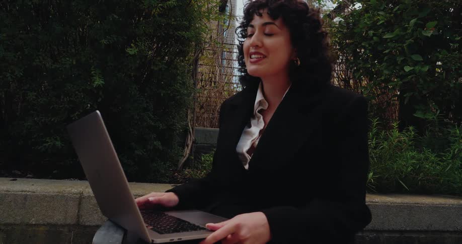 Woman attends an outdoor virtual meeting using a laptop