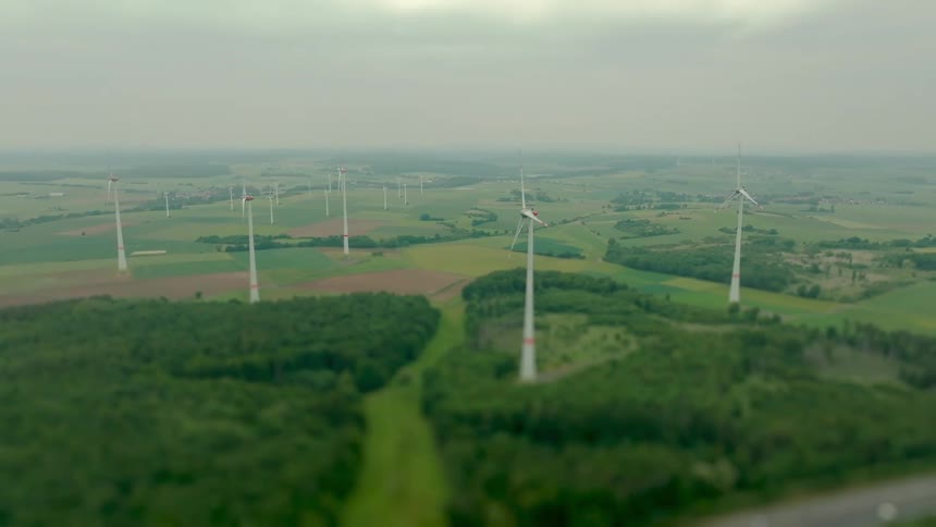 Turbines on a wind farm spin under a cloudy foggy sky