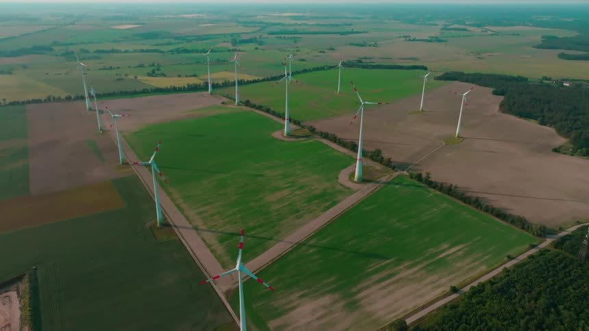 Aerial view of a wind farm stretches across flat agricultural fields