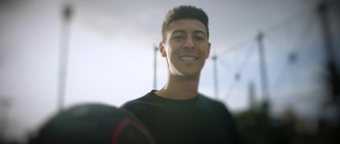A man smiles as he spins a basketball on his finger