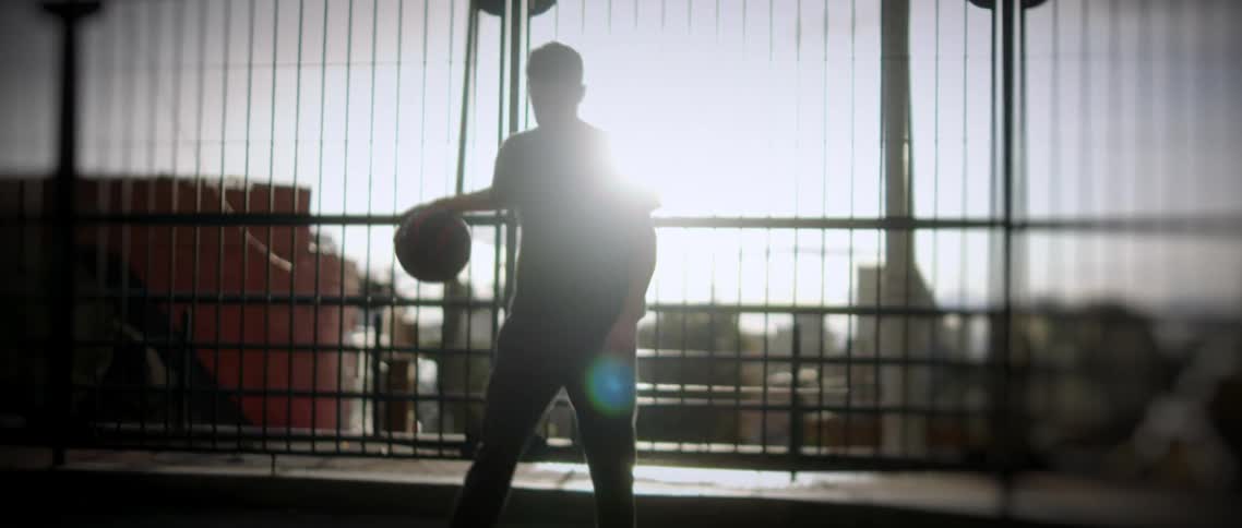 A person is playing basketball on a court in a city
