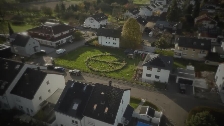 Aerial view shows a residential neighborhood with a circular grassy area in the middle