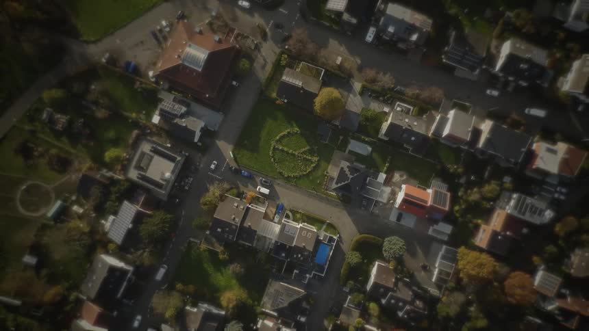Aerial view of a tree lined neighborhood with houses and a grassy field
