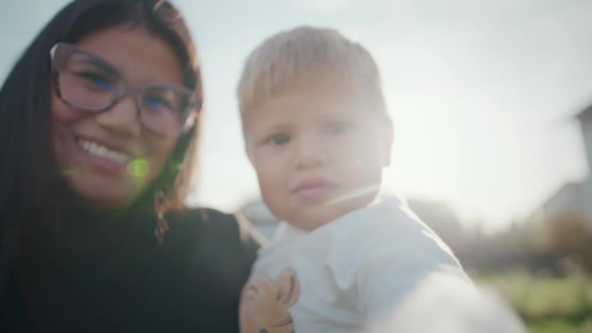 Smiling woman beside a child under natural outdoor light