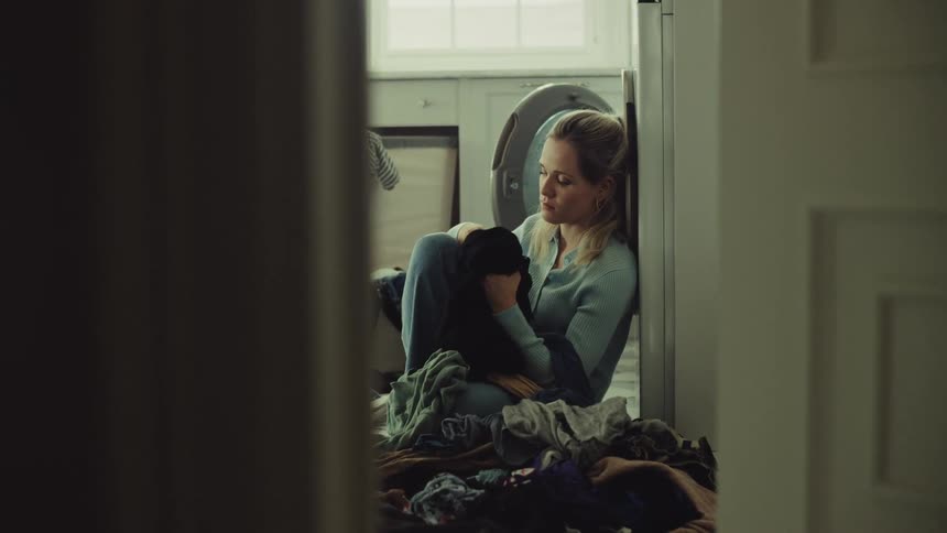 Woman sitting on the floor sorting clothes in a welllit laundry room