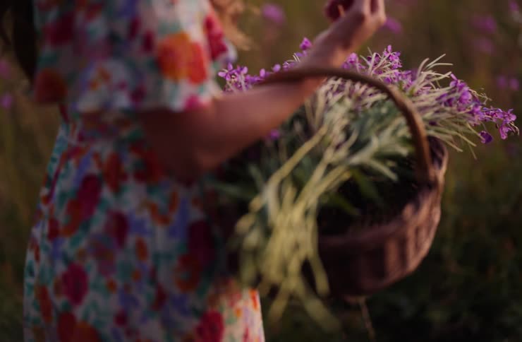 Woman holding a basket with purple flowers in a vegetated area