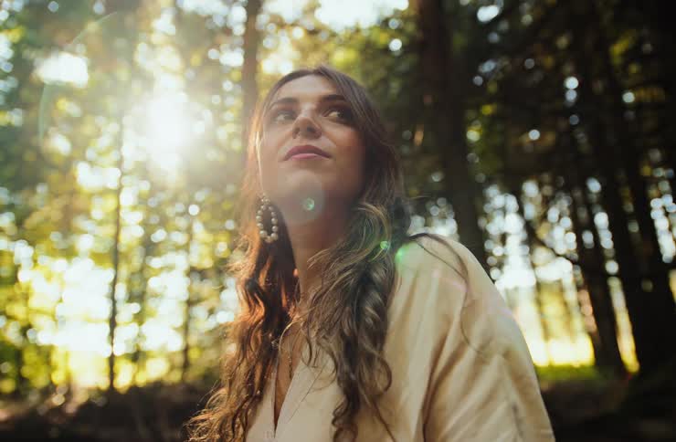 Woman in a forest area with sunlight filtering through the trees