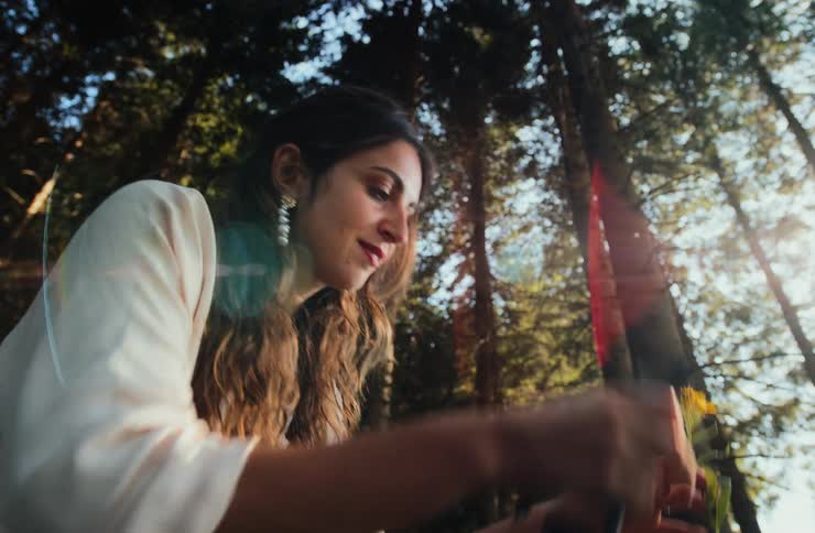Woman harvesting yellow flowers with scissors in a forest area