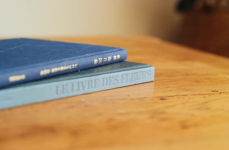 Blue hardcover books stacked on a wooden table
