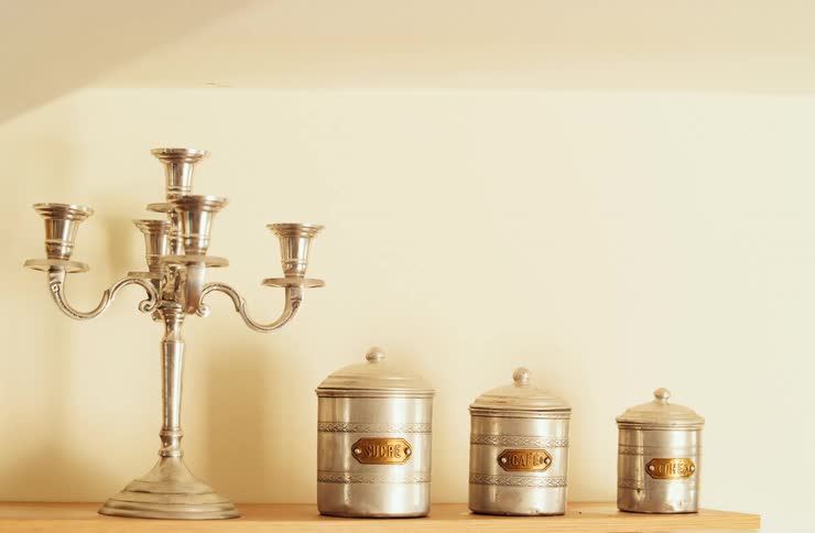 Metal candlestick beside vintage kitchen canisters arranged on the shelf