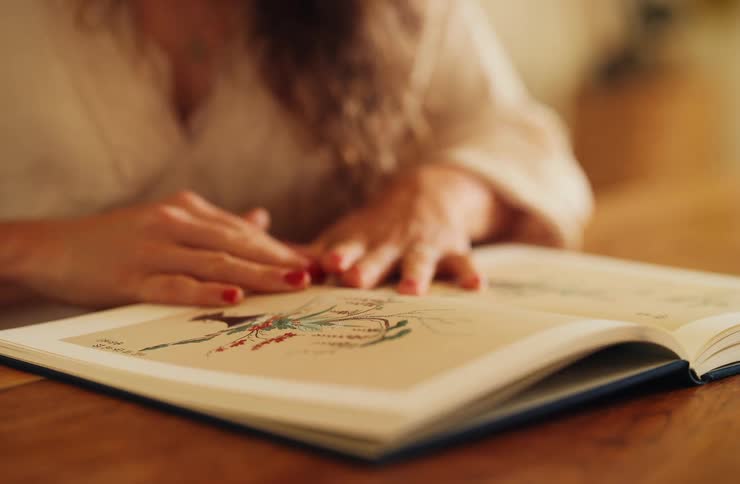 Female hands turning pages of an open book with a colorful illustration