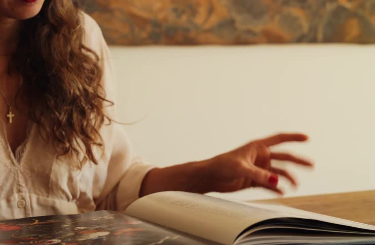 Person flipping through illustrated publication with abstract art in the background