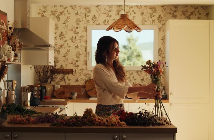 Young adult woman arranging flowers over a counter in a kitchen indoors during day time
