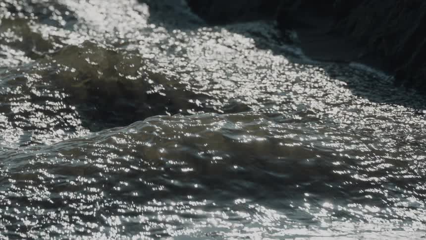 A river rushes swiftly down a slope at midday