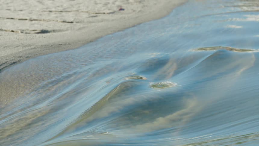 Small wave rolling over the sand at the shoreline