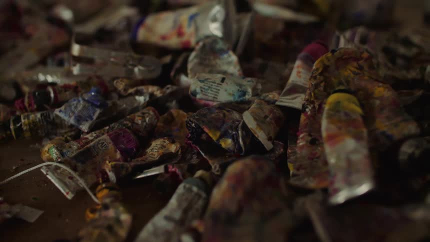 Close up of multiple used paint tubes on a table in an art studio