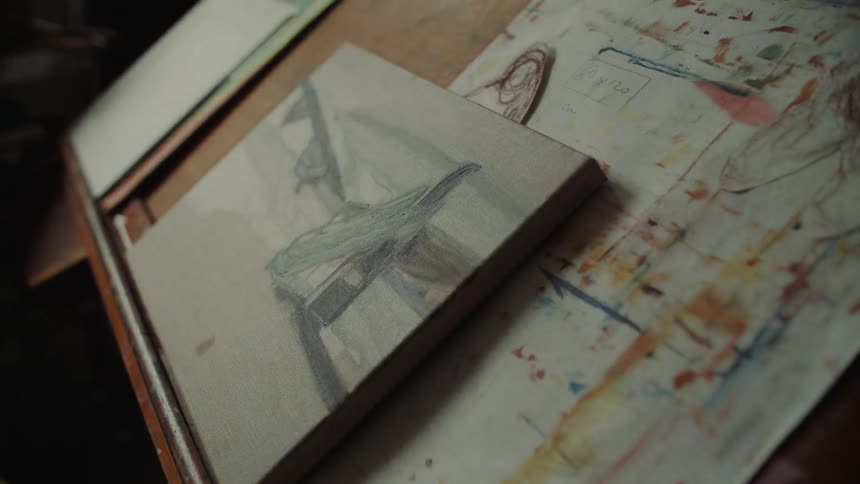 Close up of a small canvas painting on a wooden stand in a studio during daytime
