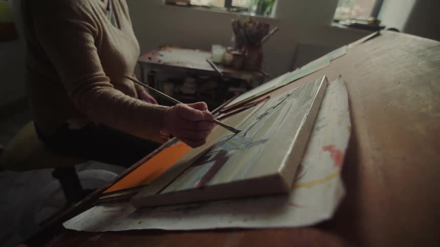 A woman paints on a canvas inside her art studio
