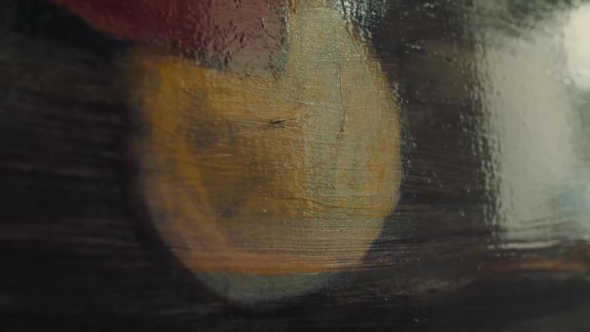 Hand applies paint on canvas with blend of dark yellow and reddish tones in artistic process