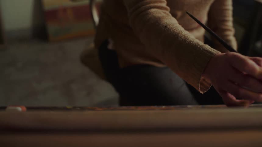 Painter applying brush strokes on a canvas on an easel