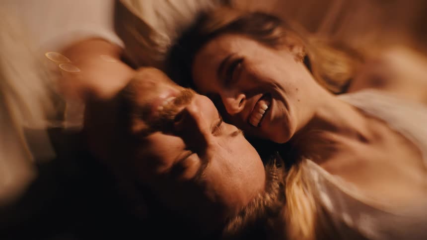 A happy couple lying down together in a dimly lit room