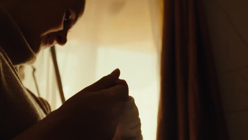 Woman feeding a baby with a bottle in softly lit surroundings