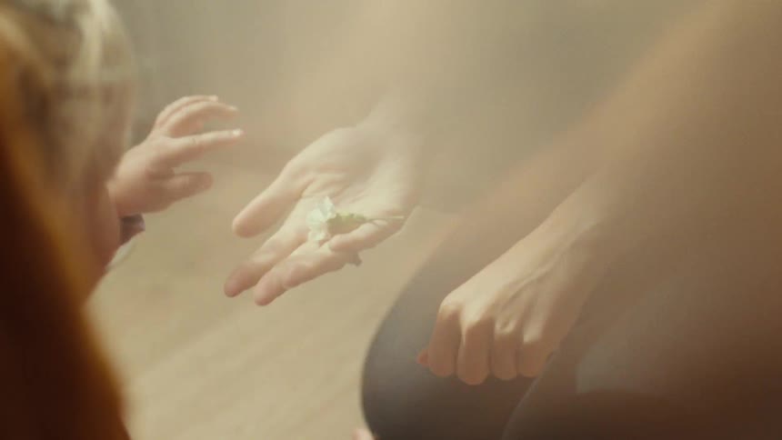 Childs hand touches adults hand under golden light in gentle setting