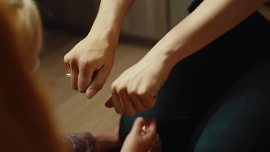 Young adult woman playing guess which hand with a baby girl and delivering her a flower indoors during day time