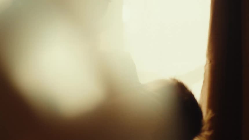 Mother holds baby in arms under soft light