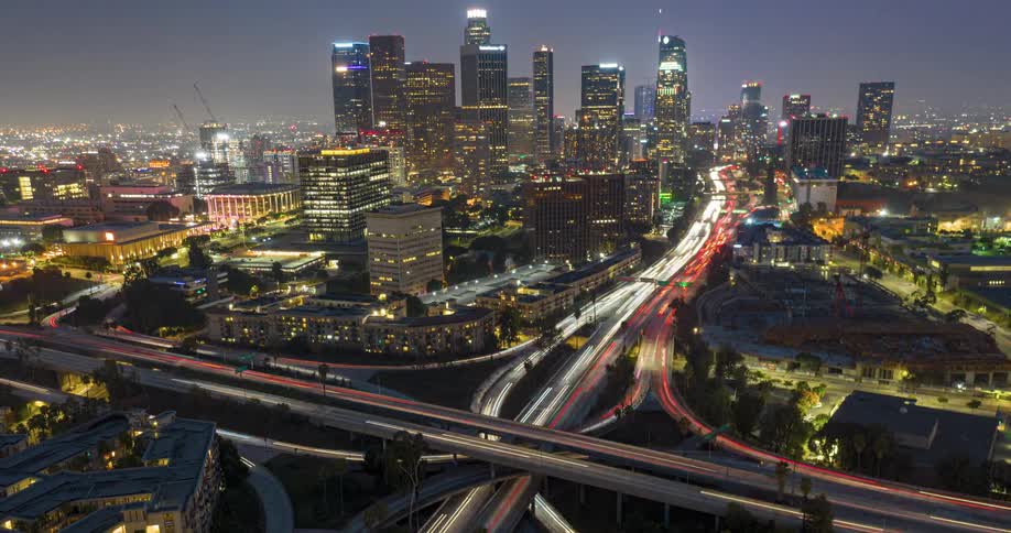 Nighttime traffic creating light trails in front of the Los Angeles skyline filled with skyscrapers