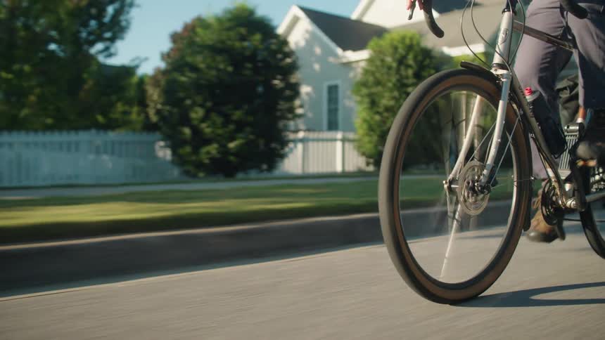 A man riding a bicycle on a road in a suburban city during daytime