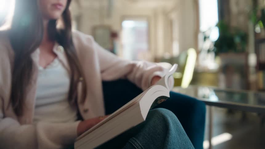 Woman reads while sitting in a room with multiple bookstores during the day
