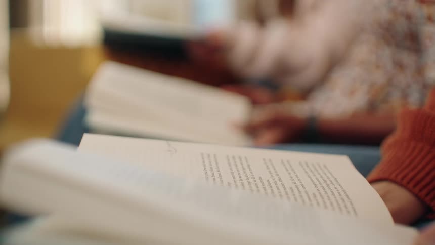 Books being read side by side by people seated in a cozy setting