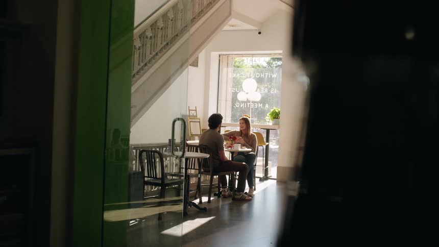 A young couple conversing while on a date in a cafe during daytime