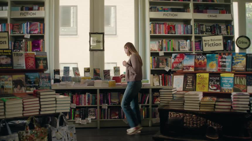 A young woman browses a display of new fiction and crime books in a bookstore
