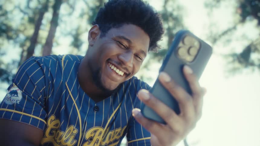 Young man holds his phone as he smiles and laughs