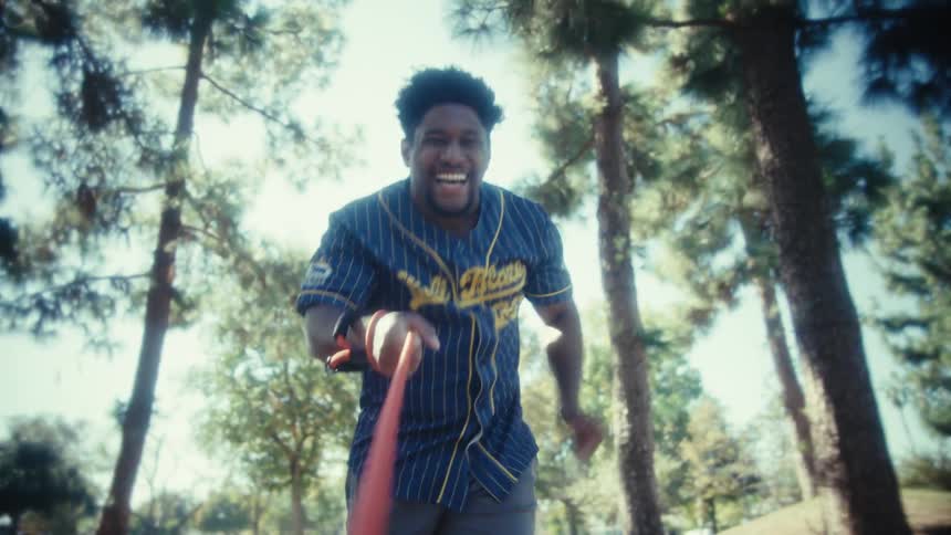 Man running and laughing while holding a dog leash in a wooded area