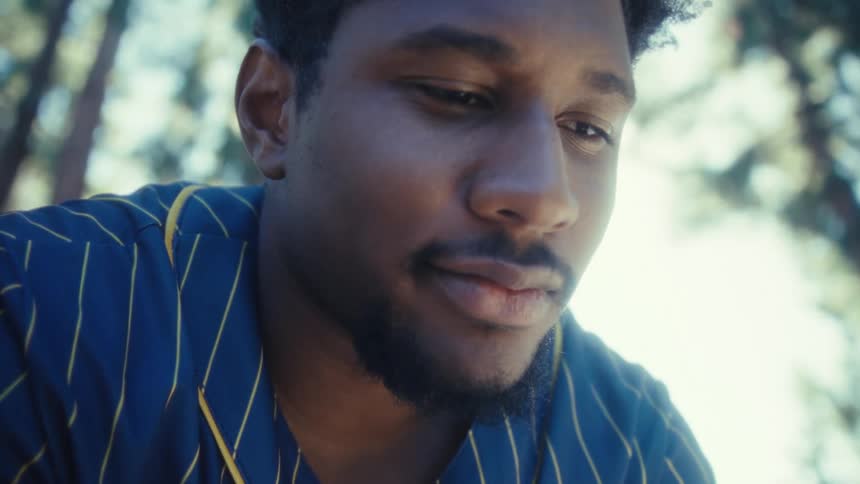 The video features a closeup of a young man wearing a navy blue and yellow pinstriped baseball jersey looking down at a smartphone he is holdinghe appears to be reading something on the phone and his expression changes from a slight smile to a wide