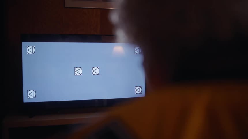 A person is raising their hand as they watch a television