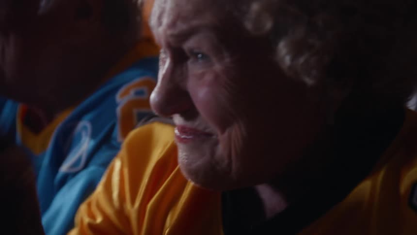 Older adults in colorful sports jerseys watching something up close