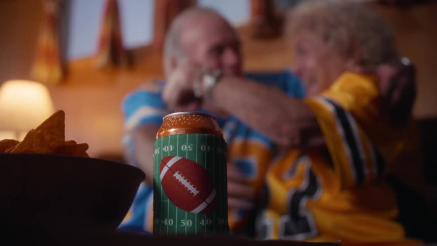 An elderly couple celebrating while watching a sports game together in a living room
