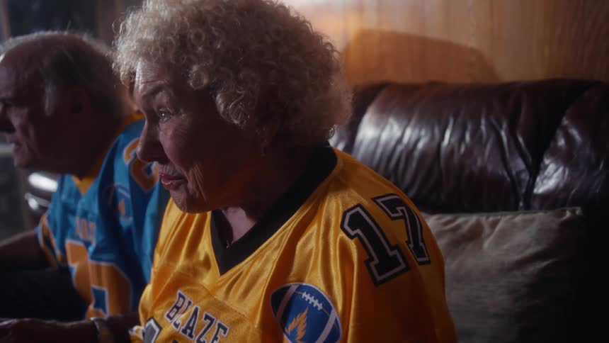 Couple wearing american football jerseys while watching the game on the couch