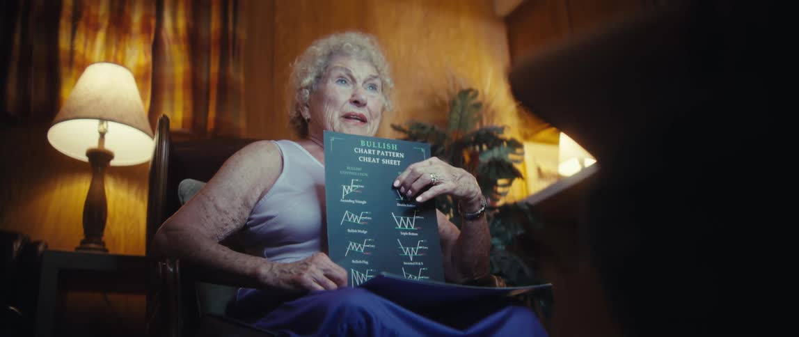 An elderly woman holds a pamphlet while sitting behind a camera giving an interview and sharing her views