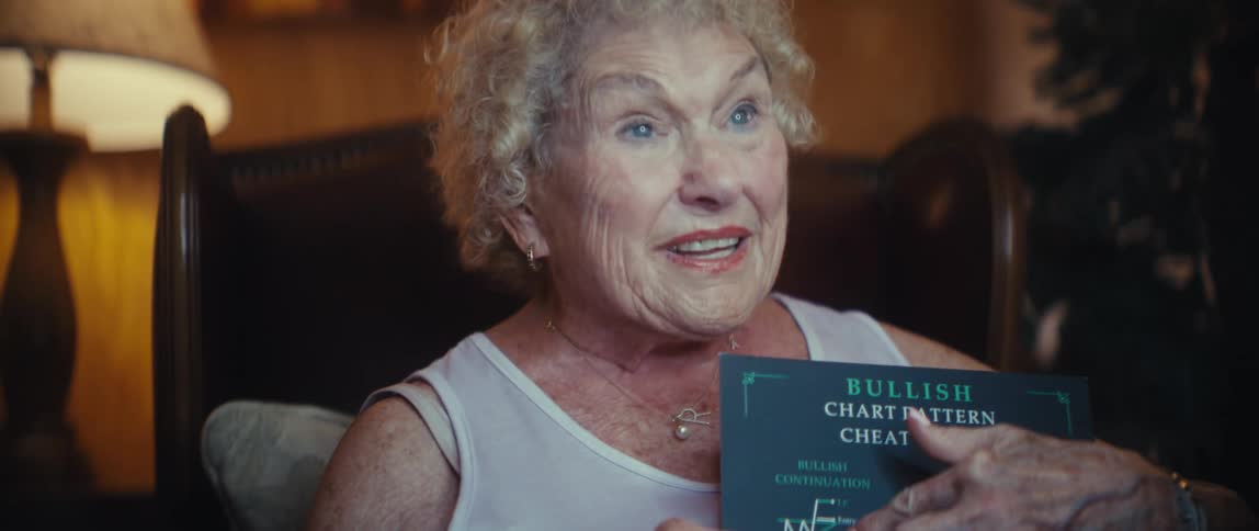 Elderly woman holding a bullish chart pattern cheat sheet while speaking enthusiastically